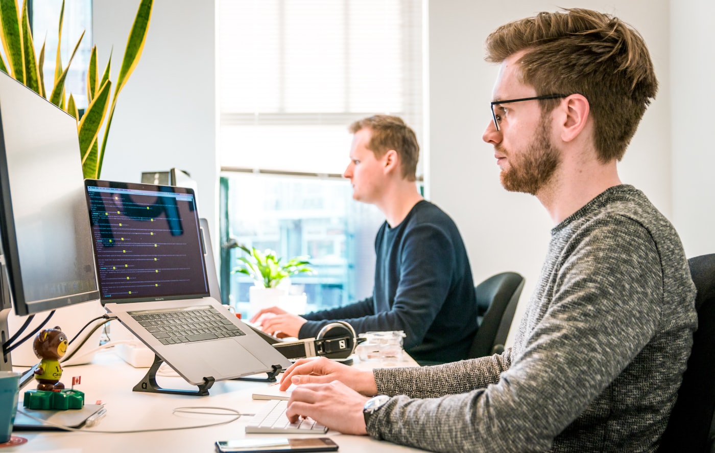 Two engineers working side by side at a shared desk