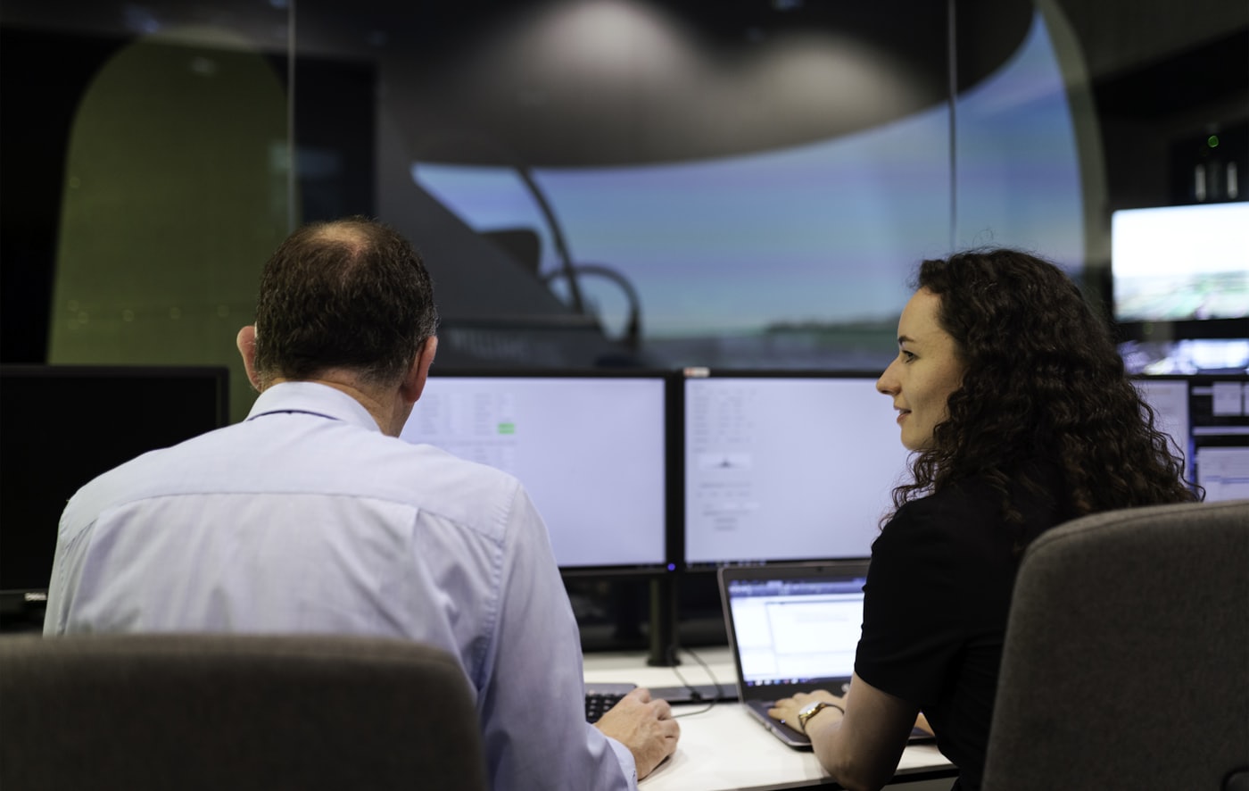 Two colleagues reviewing system dashboards in an operations room