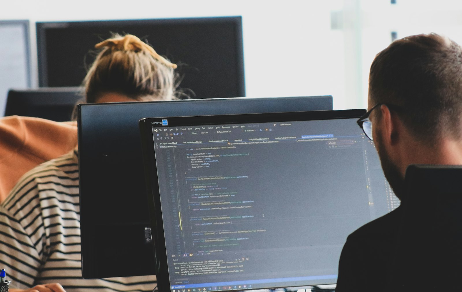 Two engineers reviewing source code on desktop monitors