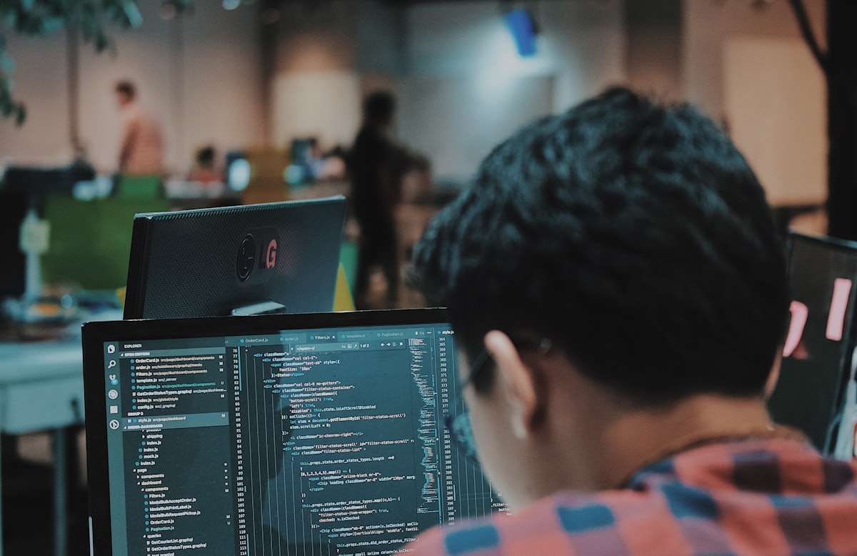 A developer writing code at a multi-monitor workstation